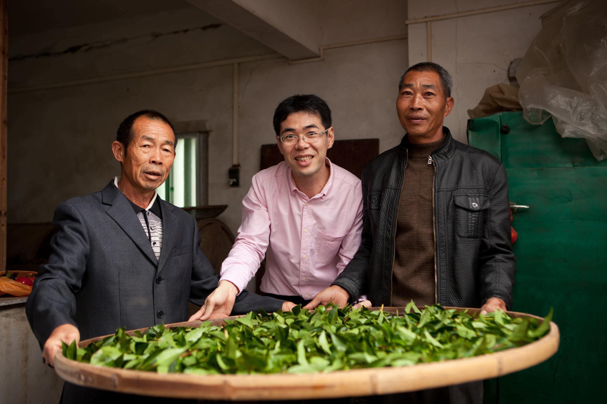 中国茶の産地で作り手と摘みたての茶葉を囲む理事長・大高勇気